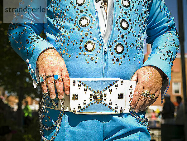 Elvis impersonator in a blue costume backstage before a performance.