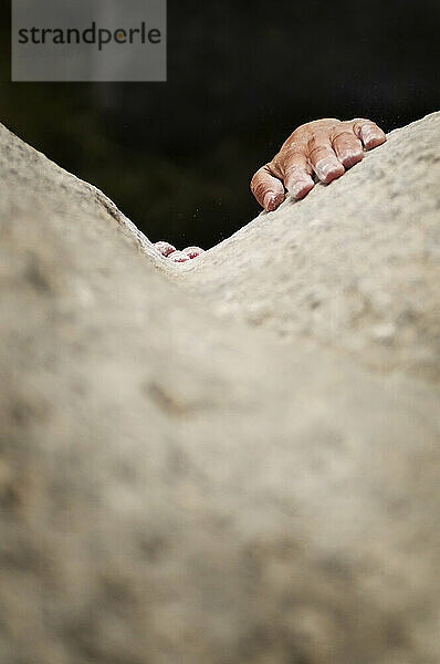 A rock climber's hands search for friction while bouldering on the smooth limestone of Californiastle Hill  New Zealand.