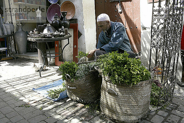 Merchant bundles herbs next to pottery shop