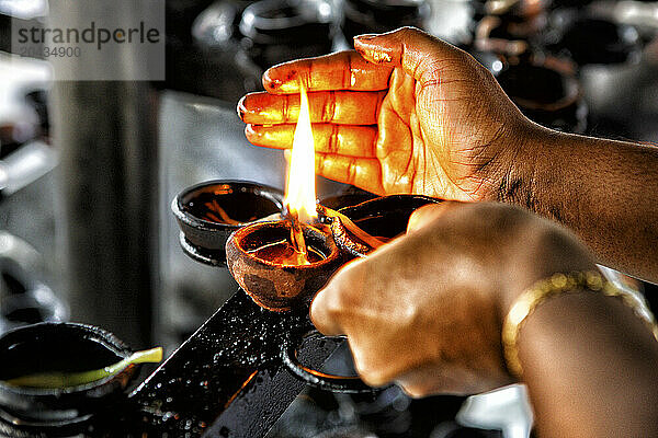 Devotee lighting candles at sunset in the Temple of the Sacred Tooth Relic - site of Buddhist pilgrimage; Kandy  Sri Lanka  Asia