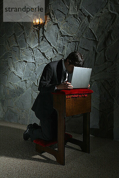 Businessman praying with laptop computer