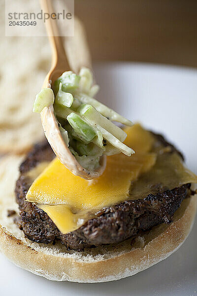 Home made hamburger with apple and celery garnish on a white plate.