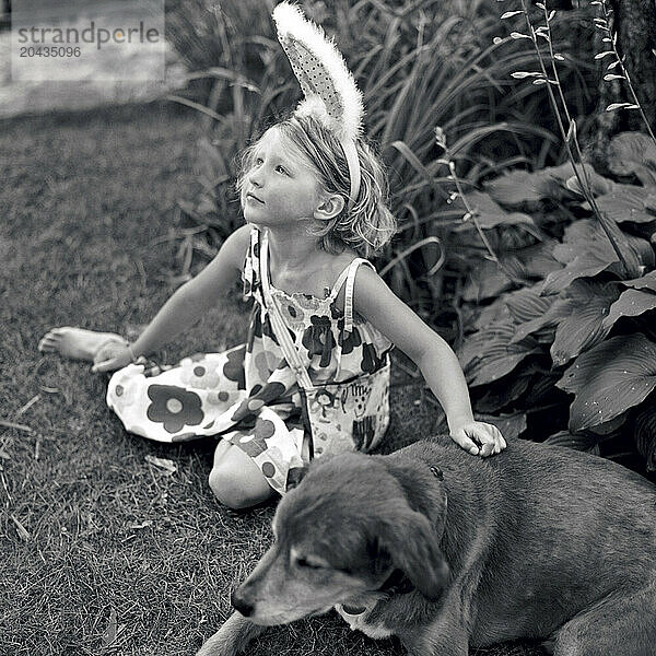 young girl sitting in grass with her dog