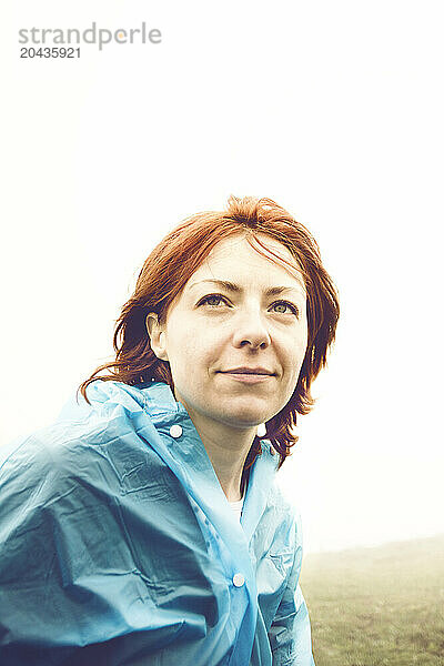 Female hiker in a blue raincoat in the fog