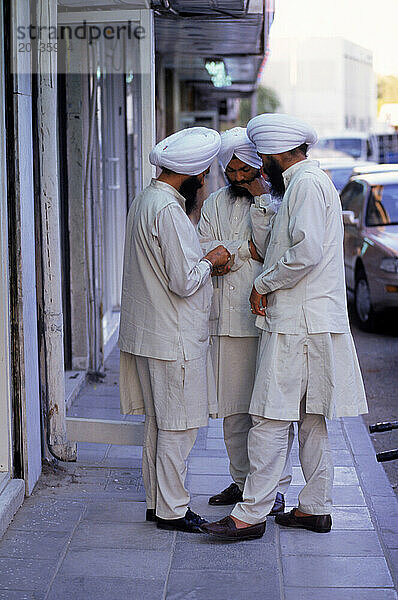 Three men converse on the streets of Dubai  Portrait of a man in Dubai  United Arab Emirates.