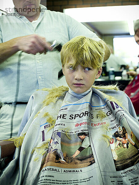 young boy gets hair cut at barber shop