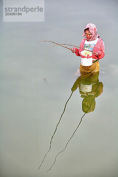 Woman fishing with two rods at a time on the Taungthaman Lake