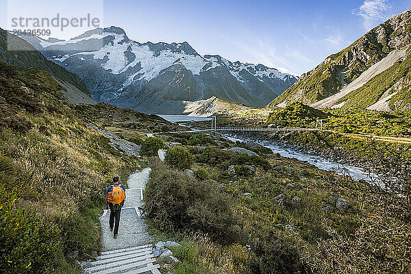 Man hiking down alpine trail towards swing bridge  Mount Cook  Canterbury  New Zealand