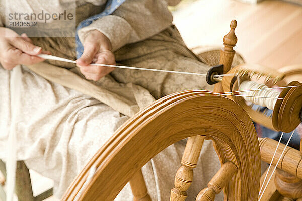 a woman spinning wool into yarn on a spinning wheel