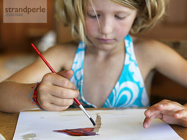 young girl paints with watercolors