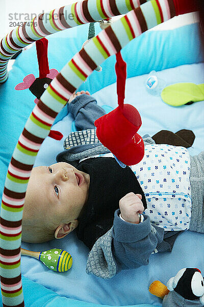 2 yr. old baby boy lying  looking at his toys