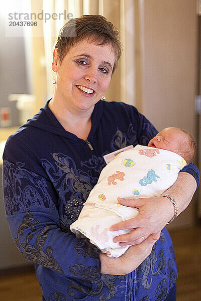 A woman holds a newborn baby in the maternity ward of a hospital.