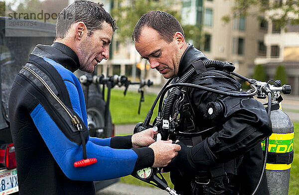 A fellow scuba diver helps another diver adjust his gear.