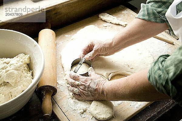 Woman making biscuits  using a biscuit cutter.