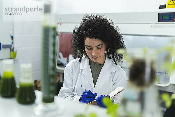 Scientist analyzing samples and taking notes in laboratory