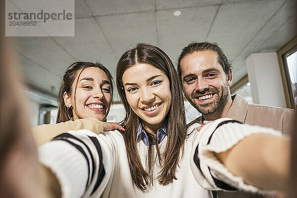 Cheerful business colleagues taking selfie at office