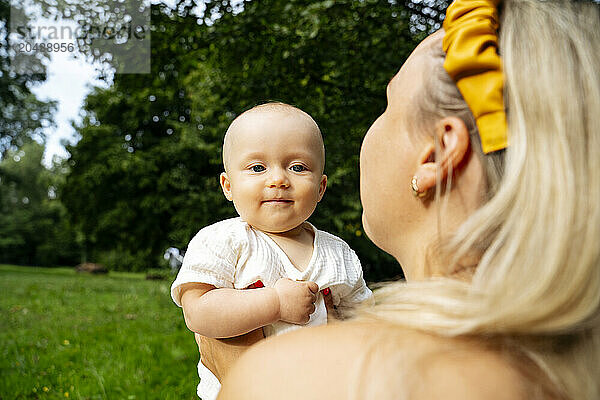 Mother holding cute baby in garden