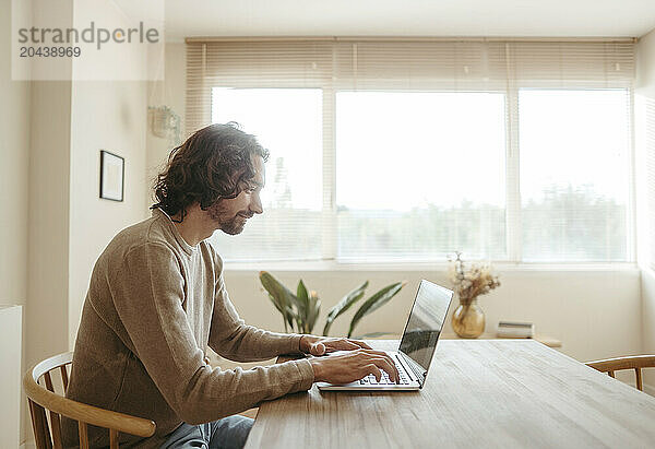 Businessman typing on laptop at table working from home