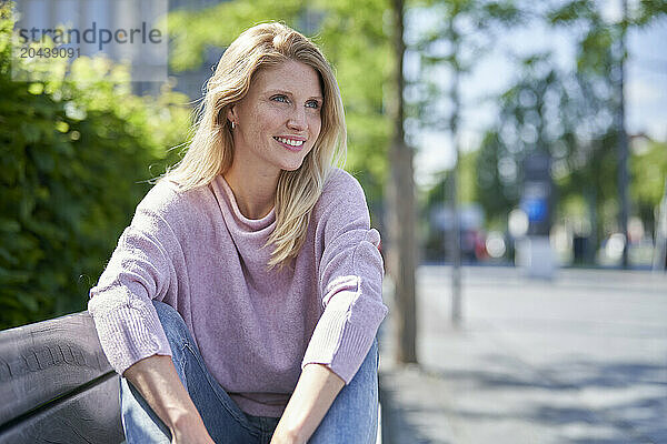 Smiling woman wearing purple sweater sitting on bench