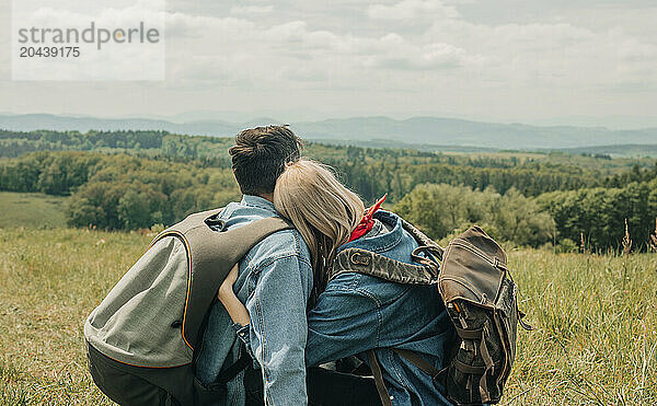 Stylish couple sitting in meadow and enjoying vacation