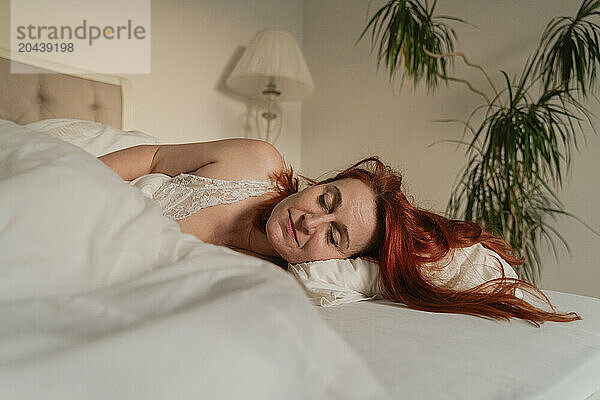 Redhead woman sleeping on bed at home