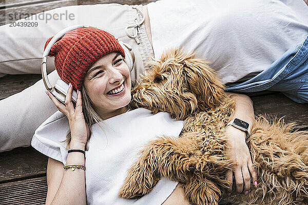 Happy woman wearing wireless headphones lying on floor