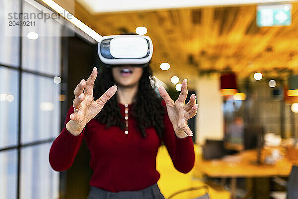 Businesswoman wearing virtual reality headset and gesturing at office