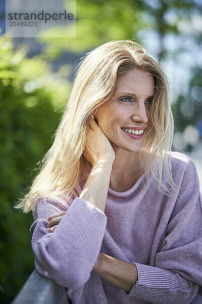 Happy blond hair woman leaning on elbow at bench