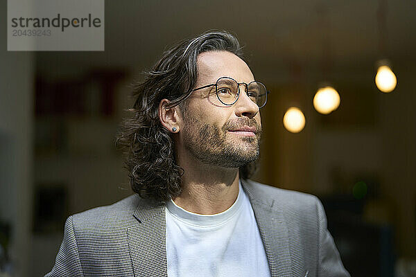 Thoughtful handsome businessman wearing eyeglasses at office