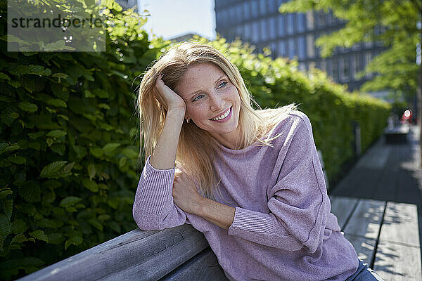 Thoughtful woman leaning on elbow and sitting on bench