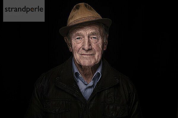 Senior man wearing hat against black background