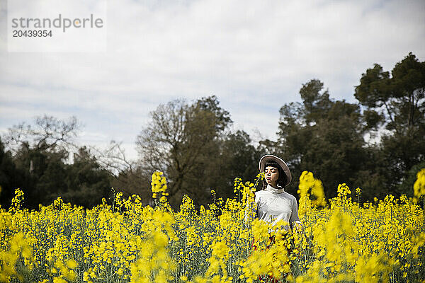 Young woman smelling rape seed flower at farm