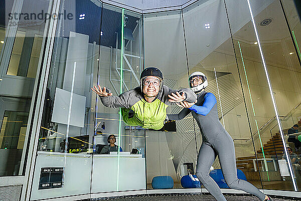 Happy woman doing skydiving with assistance of instructor at skydive center