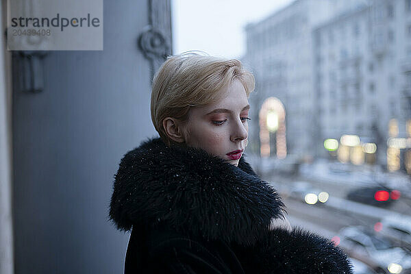 Young woman wearing black fur coat in balcony