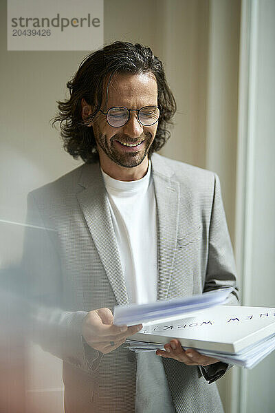 Smiling businessman examining document at office