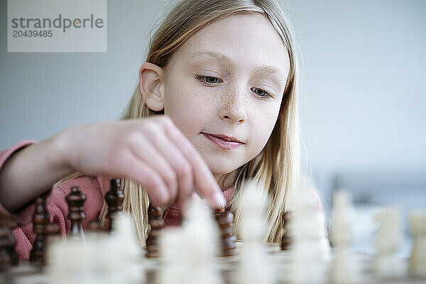 Blond girl playing chess at home