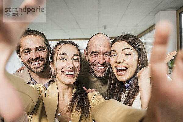 Happy cheerful business colleagues taking selfie at office