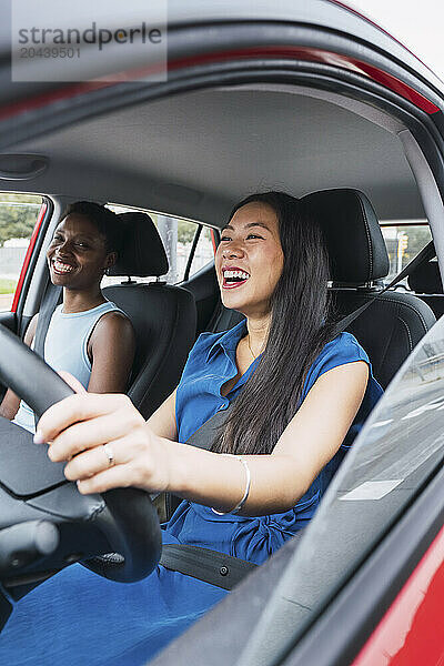 Happy multiracial female friends sitting in car