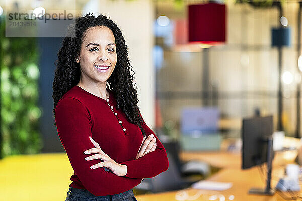 Smiling businesswoman standing with arms crossed in office