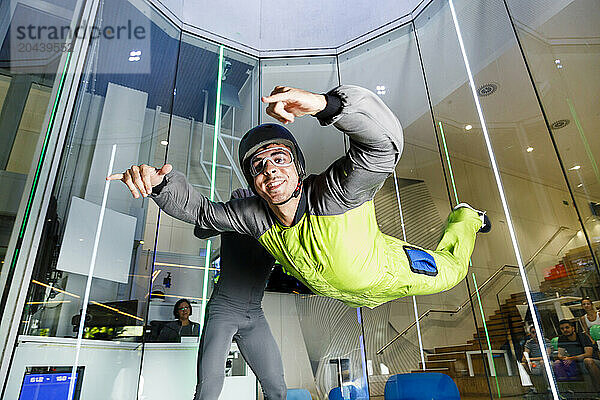 Smiling man gesturing Shaka sign and enjoying at indoor skydiving center