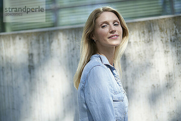 Beautiful woman with blond hair standing in front of wall