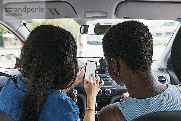 Multiracial women using GPS on smart phone in car