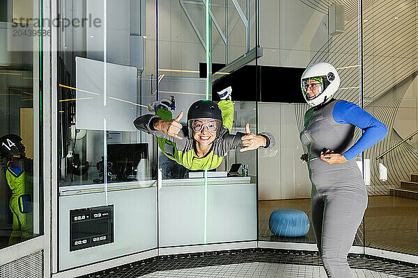 Woman flying in mid-air and gesturing at indoor skydiving center