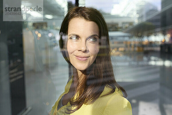 Smiling woman with brown hair seen through window at airport