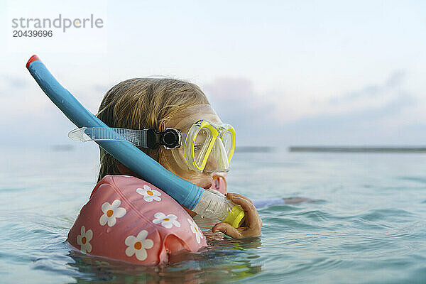 Girl snorkeling with water wings in sea