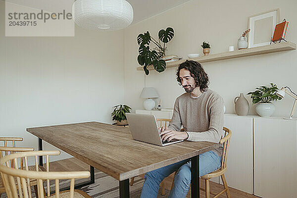 Confident businessman using laptop at table working from home