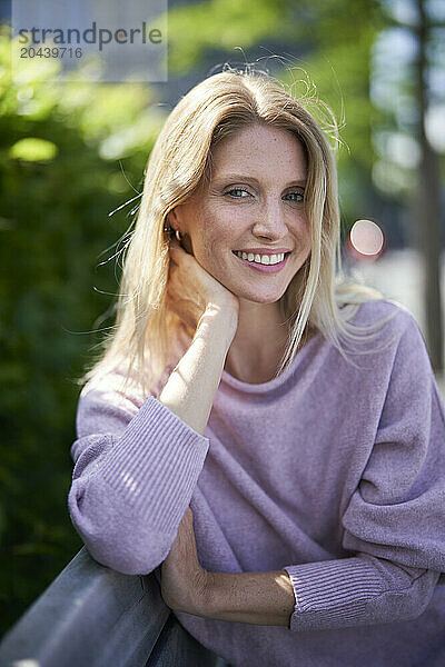 Smiling blond hair woman sitting on bench