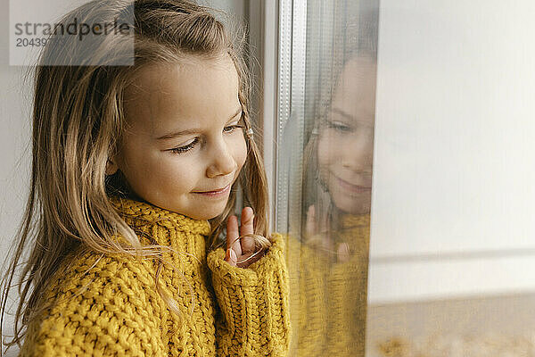 Cute girl looking through window in new apartment