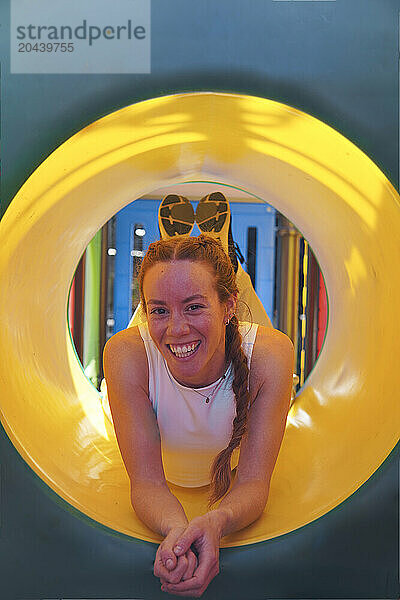 Smiling woman lying inside yellow slide