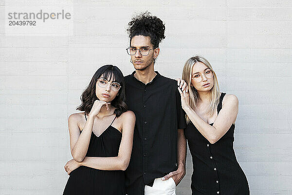 Young man with friends standing in front of white wall